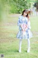 A woman in a blue and white kimono standing in the grass.