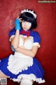 A woman in a blue and white maid outfit posing for a picture.