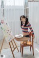 A woman sitting on a chair in front of a painting.