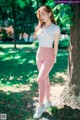 A woman standing next to a tree in a park.