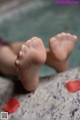 A close up of a person's feet in a bathtub with rose petals.