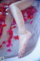 A woman's feet in a bathtub filled with rose petals.