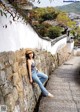 A woman leaning against a stone wall on a cobblestone street.