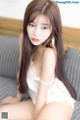 A woman in a white lingerie sitting on a couch.
