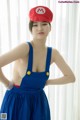 A woman in a blue dress and a red hat posing for a picture.