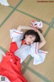 A woman in a red and white kimono laying on the floor.