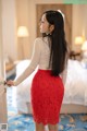 A woman in a red lace skirt standing in front of a door.