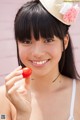 A young woman holding a cherry in her hand.