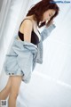 A woman in a black top and denim jacket posing for a picture.