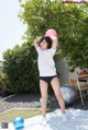 A woman in a white shirt and blue shorts holding a pink ball.