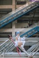 A woman in a white dress sitting on a metal structure.