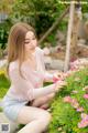 A woman sitting on the ground next to a bunch of flowers.