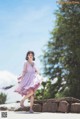 A woman in a purple dress is walking on a stone wall.