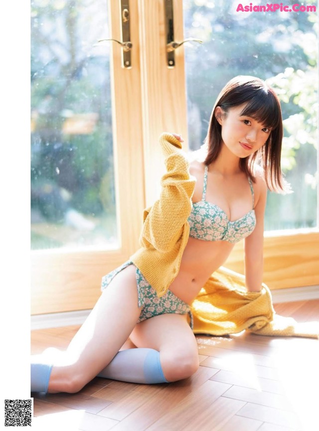 A woman in a bikini sitting on the floor.