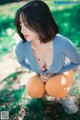 A woman in a blue shirt and orange pants crouching on the ground.