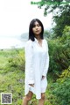 A woman in a white shirt dress standing in a field.