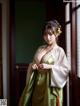 A woman in a green and white kimono standing by a window.