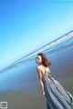 A woman in a blue and white dress standing on a beach.