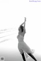 A woman in a white dress is dancing on the beach.
