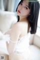 A woman in a white lingerie sitting on a couch.
