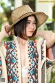 A woman wearing a straw hat and a colorful cardigan.