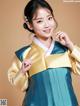 A woman in a blue and gold hanbok poses for a picture.