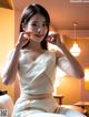 A woman in a white dress sitting on a bed.