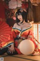 A woman in a red and black kimono sitting on the floor.