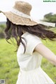 A woman in a white dress and a straw hat.