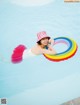 A woman in a pink hat floating in a pool with an inflatable ring.