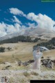 A woman in a white dress holding an umbrella on top of a mountain.