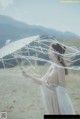 A woman in a white dress holding an umbrella.