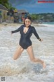 A woman in a wet suit jumping in the water.