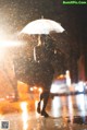 A woman walking in the rain holding an umbrella.