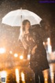 A woman standing in the rain holding an umbrella.