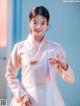 A woman in a pink and white hanbok poses for a picture.