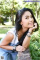 A woman leaning against a stone wall in a park.