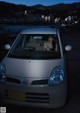 A woman sitting in the driver's seat of a small car.