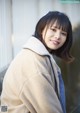 A woman in a beige coat posing for a picture.