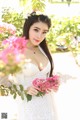 A woman in a white dress holding a bunch of flowers.