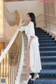 A woman in a white dress standing on a staircase.