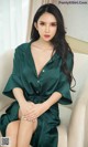 A woman in a green dress sitting on a white chair.