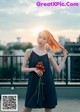 A woman in a black dress holding a flower.